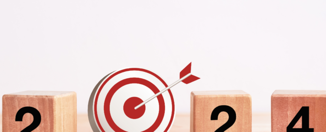 Drei Holzklötze mit den Ziffern zwei und vier und eine Zielscheibe mit Pfeil, die eine null darstellt, was auf das neue Jahr 2024 hinweisen soll.