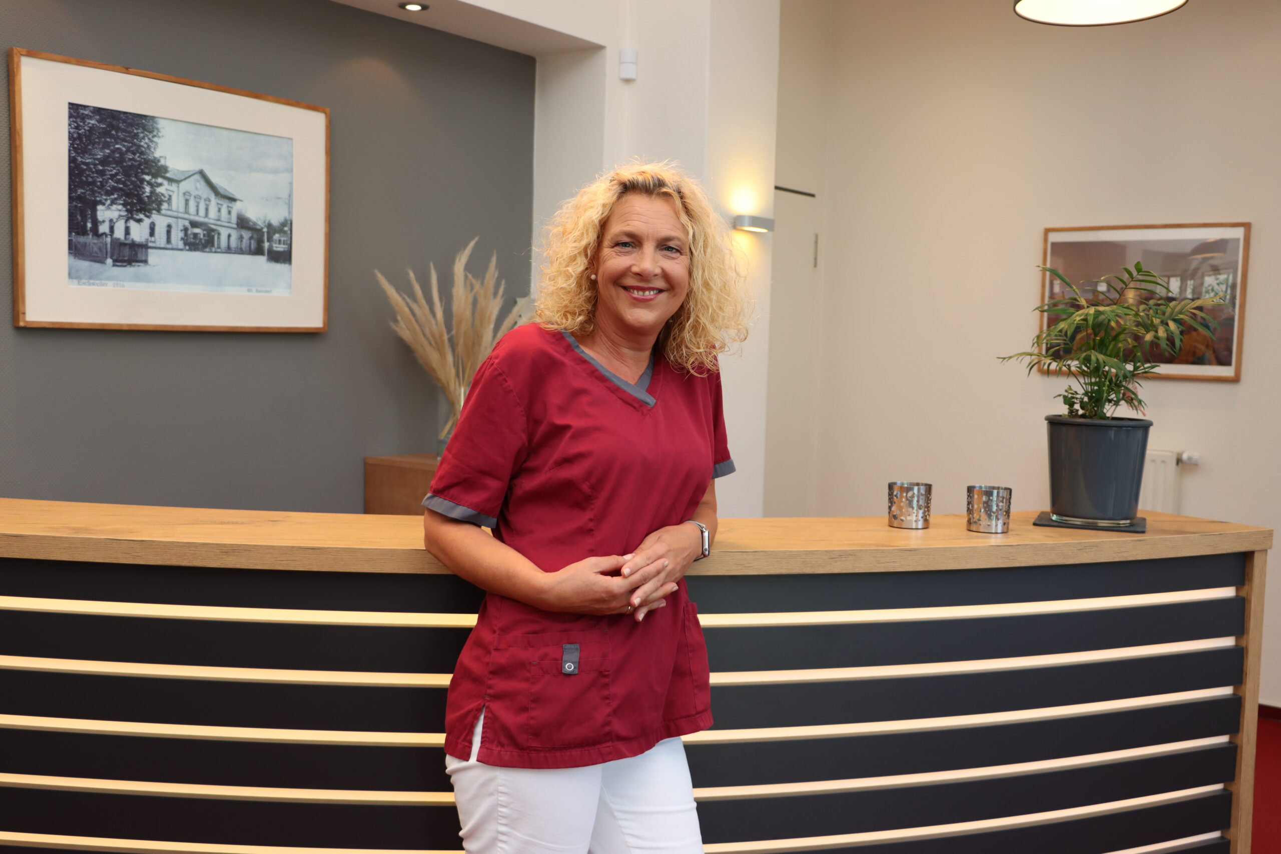 Bauhammer ZMF Diana Bauhammer lehnt an der Empfangstheke der Praxis für Zahnheilkunde Susanne Rhiem.
