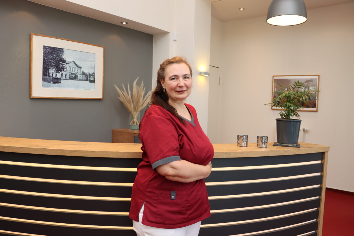 Meisner ZFA Elena Meisner lehnt an der Empfangstheke der Praxis für Zahnheilkunde Susanne Rhiem.