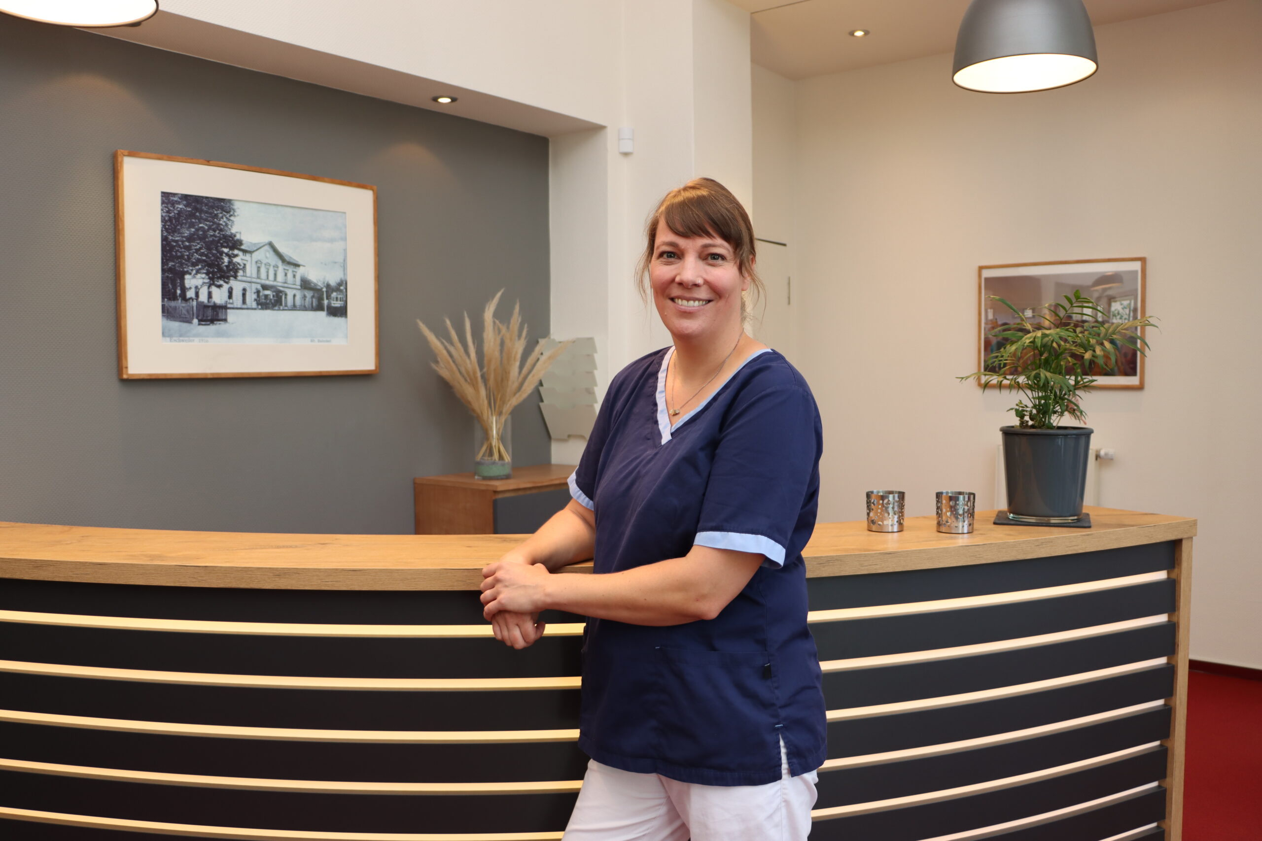 Sprehe Zahnärztin Nikola Sprehe lehnt an der Empfangstheke der Praxis für Zahnheilkunde Susanne Rhiem.