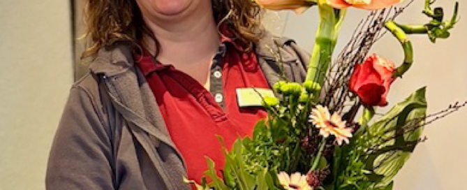 Neues aus dem Blog: Rezeptionistin Andrea Mock hält einen Blumenstrauß in der Hand, den sie zu Ihrem fünfjährigen Dienstjubiläum bekommen hat.