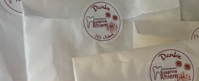 Für zehn Jahre Treue gab es zum Praxisjubiläum kleine Tütchen mit einem Aufkleber darauf, die im Bild übereinander liegen.