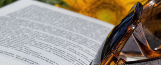 Aufgeschlagene Buchseite mit Sonnenbrille und Sonnenblume.